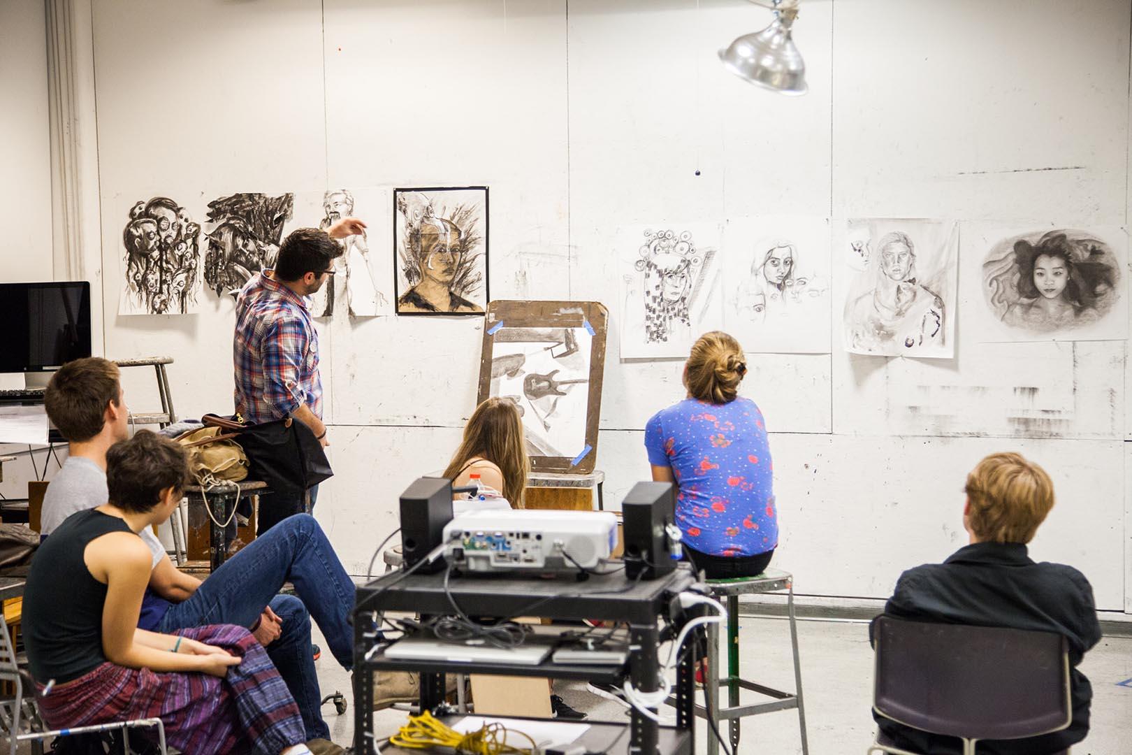 Fine arts class with faculty and students looking over drawings
